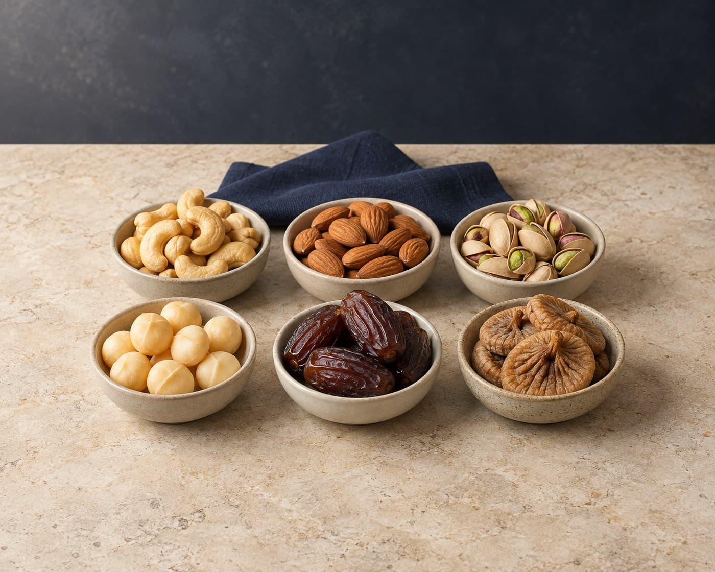 Cashews, almonds, pistachios, macadamias, Medjool dates and dried figs in separate bowls